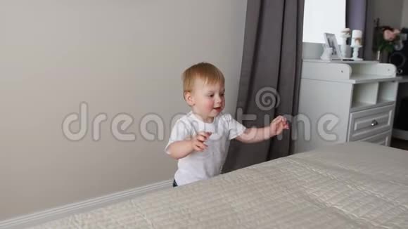 这个男孩站在父母床前和父母一起玩视频的预览图