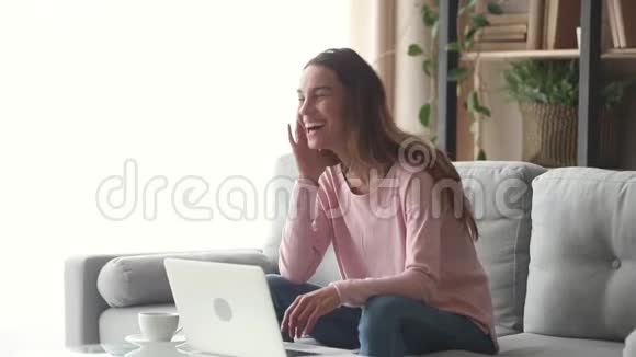 快乐的年轻女子笑着看着笔记本电脑屏幕看喜剧视频的预览图