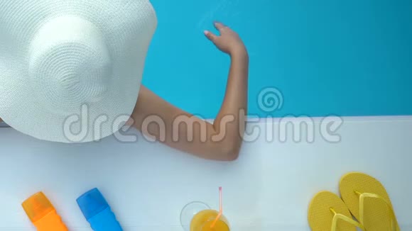 戴大白帽子的女性在游泳池玩水在酒店度假视频的预览图