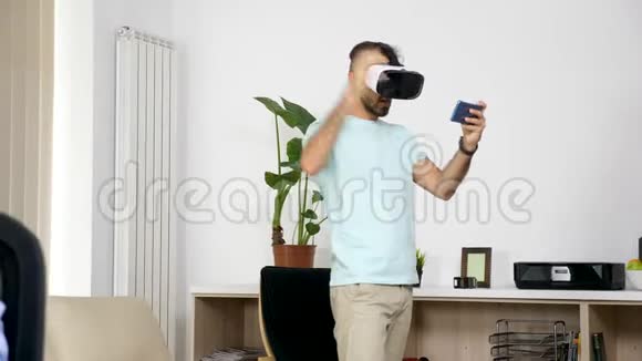 男人在客厅玩虚拟现实游戏而她的女朋友在电脑上工作视频的预览图