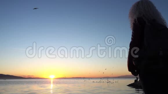 孤独的女人站着看美丽的海景视频的预览图