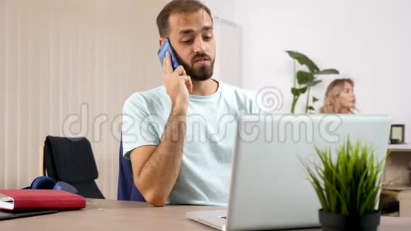 当妻子在控制台上玩电子游戏时一个男人拿着手提电脑在电话上交谈视频的预览图