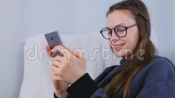 戴眼镜的年轻黑发女人在手机上输入一条信息视频的预览图