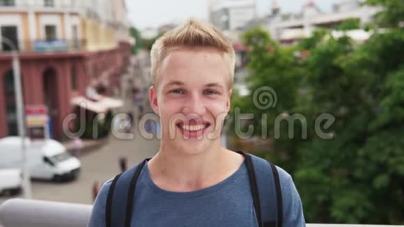 年轻快乐的男学生微笑着看着城市大街的镜头视频的预览图