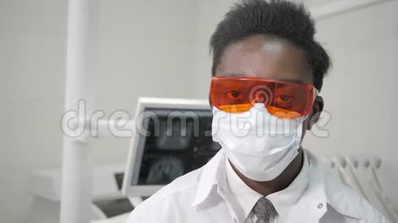 戴上医用橙色安全眼镜年轻的非裔美国男医生戴着医用面具的牙医医学卫生视频的预览图