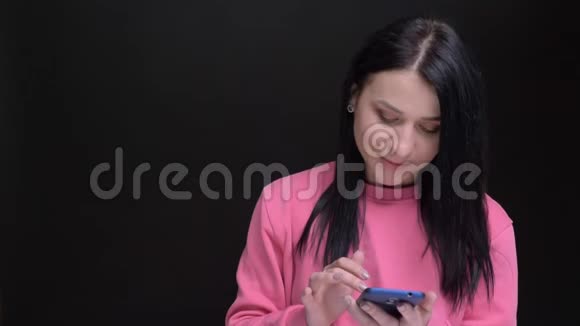 年轻美丽的白种人女性的特写肖像用手机回应社交媒体的评论笑着看着视频的预览图