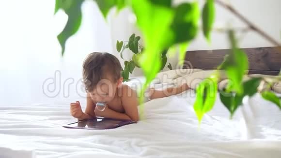 小男孩看着躺在床上的平板电脑视频的预览图