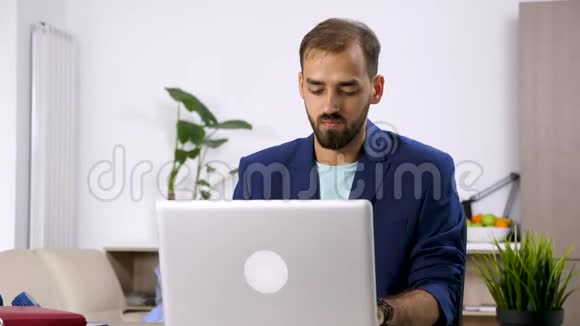 穿西装的男人在电脑上工作而女人在后台看电视视频的预览图