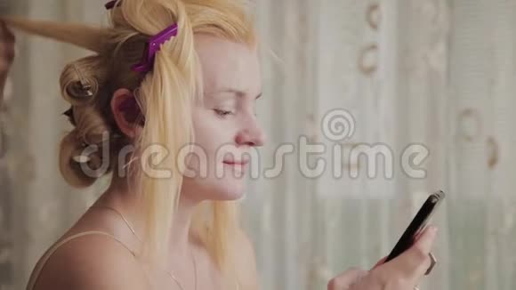 专业的理发师女士正在做一个模特的发型照片她手里拿着一个电话视频的预览图