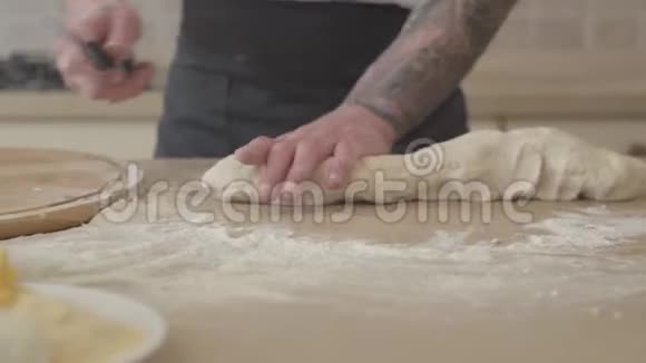 在现代厨房里年轻的披萨师傅用大刀切披萨的面团橄榄油视频的预览图