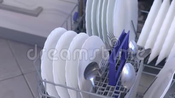 在厨房的内置洗碗机篮子里清洗白色盘子和餐具视频的预览图