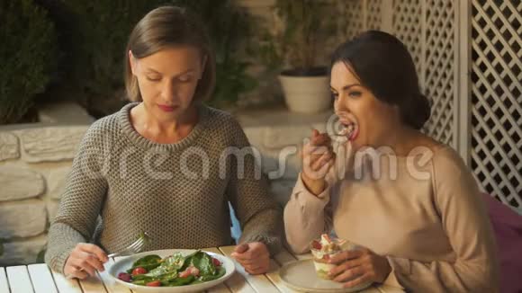 女士逗女朋友吃蔬菜沙拉和甜奶油甜点视频的预览图