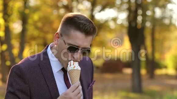 成功的年轻商人在秋天公园散步吃冰淇淋视频的预览图