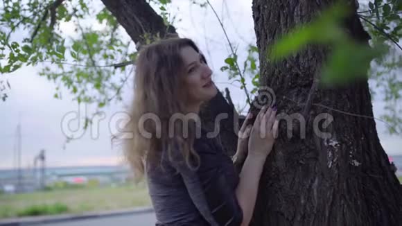 站在树旁边的女人阴天视频的预览图