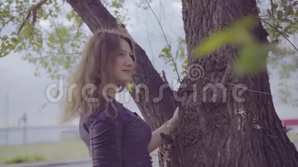 站在树旁边的女人阴天视频的预览图