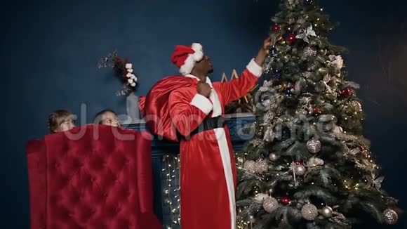 圣诞老人把玩具放在圣诞树上而两个女孩为他偷窥视频的预览图
