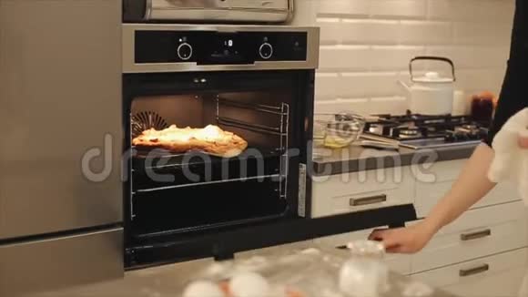 女人把披萨放进黑烤箱里在家做饭视频的预览图