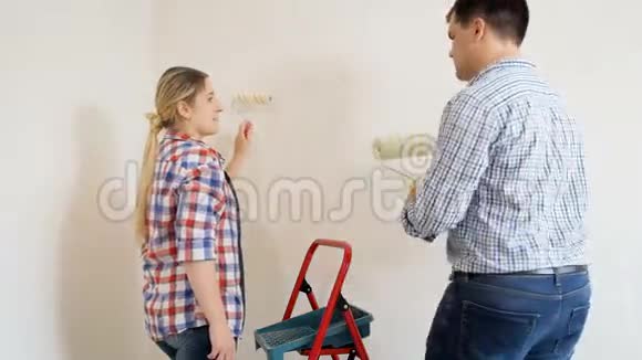 一对幸福的年轻夫妇正在装修他们的新公寓用油漆滚筒粉刷墙壁视频的预览图