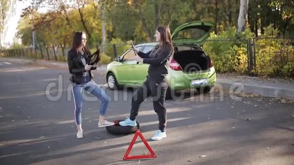 两个女人在路边用一个破碎的轮子在汽车附近跳舞引起了司机的注意视频的预览图