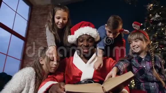 穿着圣诞老人服装和孩子们一起读书的非洲男孩的肖像视频的预览图