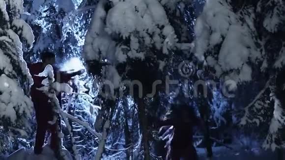 可爱的男人和女孩穿着红色的衣服在白雪皑皑的冬林中慢慢移动视频的预览图