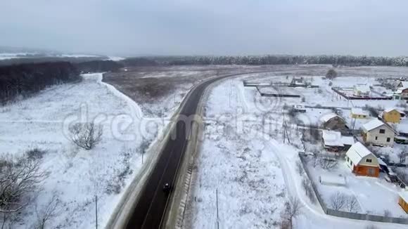 黑车在降雪时骑在高速公路上在长时间右转进入冬季森林空中观景视频的预览图