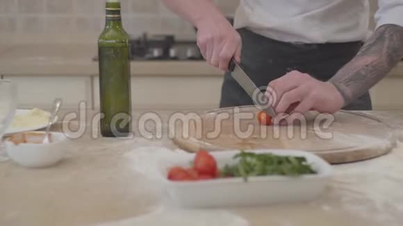 一个面目全非的男人把切西红柿的樱桃切成披萨躺在桌子上食物概念视频的预览图