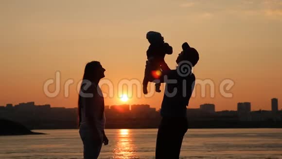 日落时分一个年轻的家庭在河边嬉戏视频的预览图