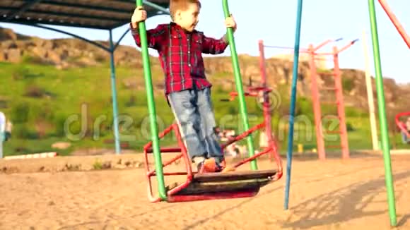 穿牛仔裤的小男孩在秋千上玩视频的预览图