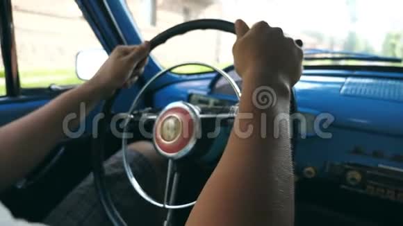 在一辆复古车的方向盘上闭上男性的手一个面目全非的人在城市大街开着一辆老式汽车视频的预览图