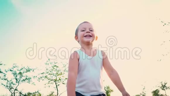 四岁的男孩穿着一件白色的t恤笑着孩子跳上天空活泼开朗的孩子对大自然的描绘视频的预览图