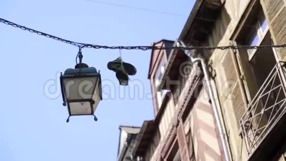 运动鞋挂在电线上行动悬挂在房屋和蓝天背景电缆电线上的运动鞋恶霸们视频的预览图