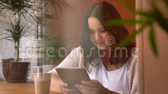 浓白俄罗斯妇女在咖啡馆的窗口边拿着计划和喝着咖啡视频的预览图
