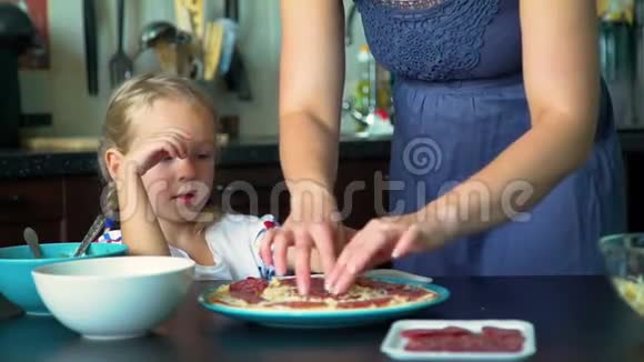小女孩把沙拉米放在披萨基地视频的预览图