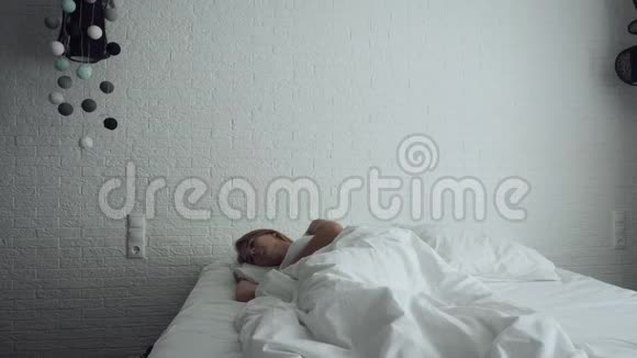女人醒来在舒适舒适的床上伸展和起床视频的预览图