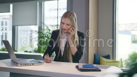时髦的商务女性看笔记本电脑和打电话时尚的金发女郎在餐桌上工作视频的预览图