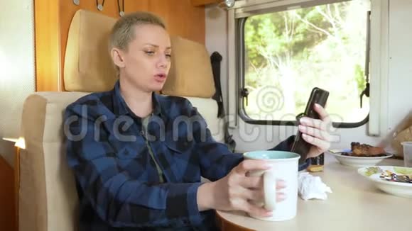 一个女人坐在汽车屋的桌子旁用手机视频的预览图