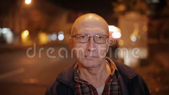 夜晚城市灯光和汽车中的一位老人的肖像视频的预览图