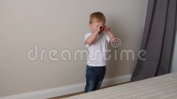 这个男孩站在父母床前和父母一起玩视频的预览图
