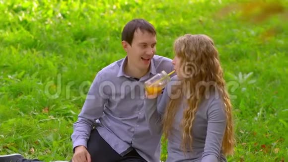 公园里的男人和女人喝果汁玩笑视频的预览图