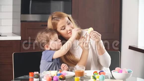 妈妈和儿子画鸡蛋一家人坐在厨房里准备复活节视频的预览图