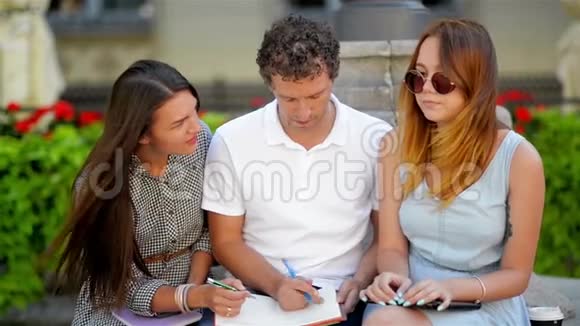 户外滑稽微笑青年学生坐在城市公园的壕沟上准备考试的画像视频的预览图