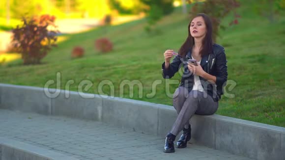公园里迷人的女孩画着她的嘴唇看着手机里的倒影准备约会视频的预览图