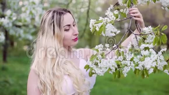 金发女人用花蕾抚摸树枝视频的预览图