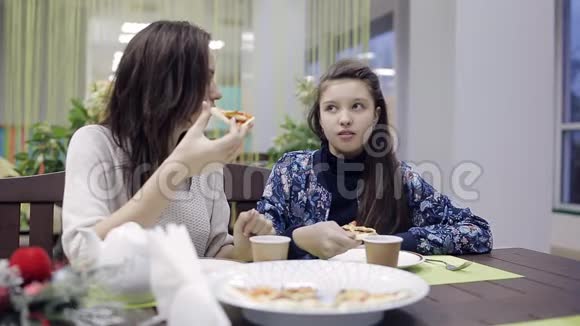 美丽的母亲和女儿一起吃披萨愉快地交谈视频的预览图