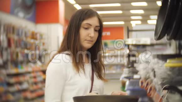 年轻女子在店里选择煎锅视频的预览图