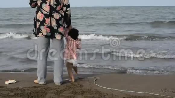 带尿布的母婴在海滩散步的背景视频的预览图