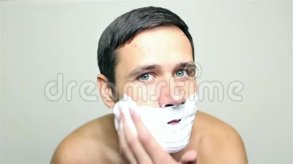 年轻的帅哥用剃须泡沫来刮胡子视频的预览图