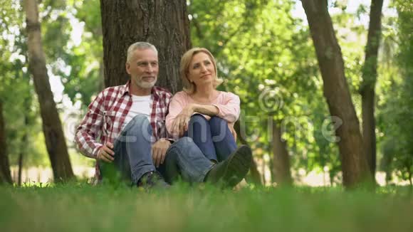 乐观的退休夫妇在公园的草地上放松计划暑假视频的预览图