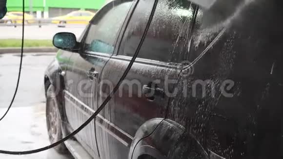 一个人洗了一辆黑色的车自助洗车过程中的慢动作视频用水喷射视频的预览图